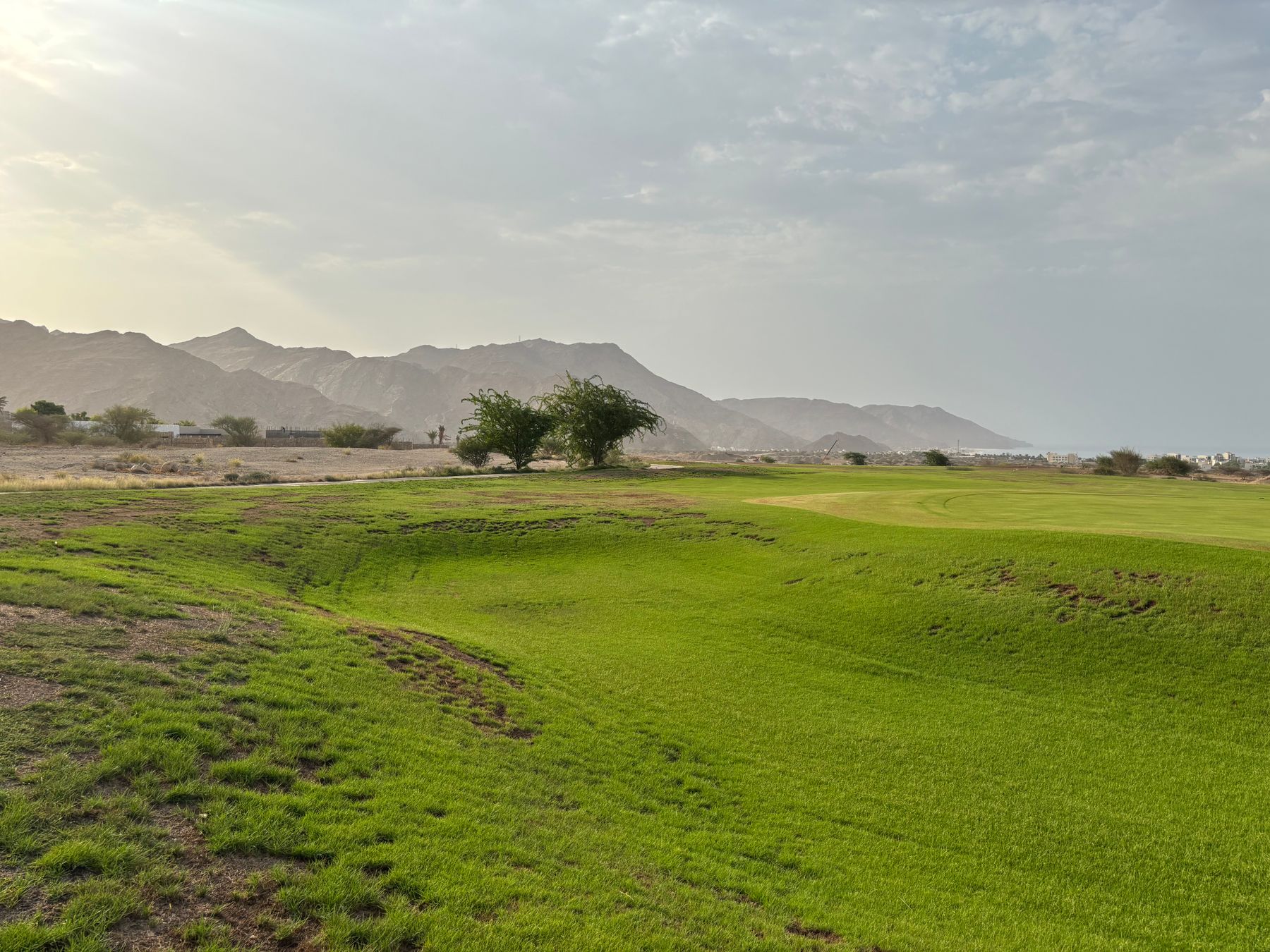 Green golf fairway against a rugged desert mountain landscape