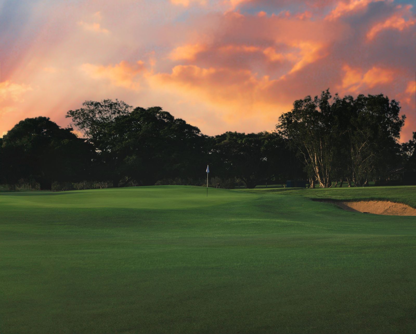 Smooth putting green under a glowing sunset sky